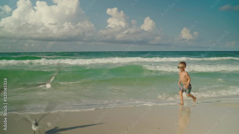 Little boy is running playing with seagulls on the beach. Boy and seagulls. Panama City Beach Little boy is running playing with seagulls on the beach. Boy and seagulls. Panama City Beach