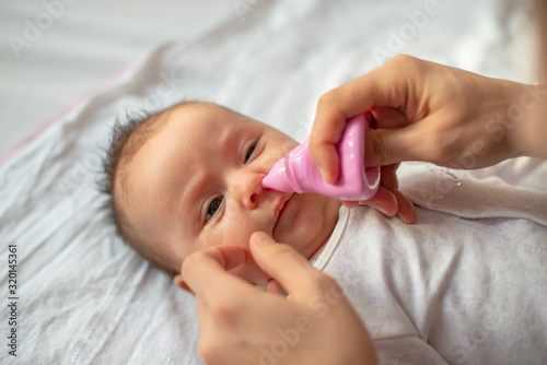 mother using baby nasal aspirator mucus nose suction