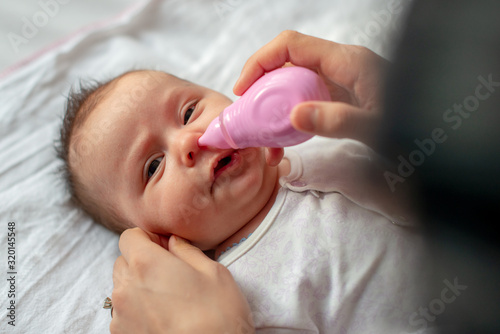 mother using baby nasal aspirator mucus nose suction photo
