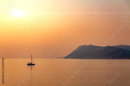 Sunset on the background of the boat and mountains. © Oleg