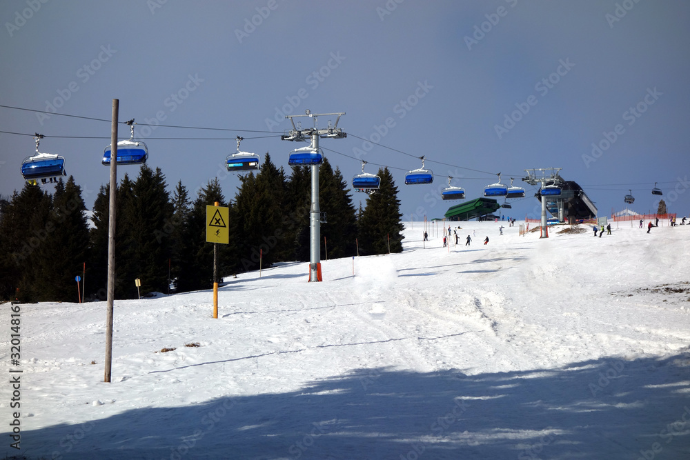 Schönes Wetter im Skigebiet Feldberg im Schwarzwald. Beschneite Piste mit Skilift und einigen Skifahrern weiter oben am Berghang