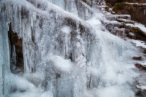 Amazing, close-up view of completely frozen waterfall, beautiful details of frozen water and icicles hanging from the cliff