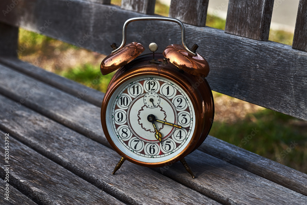 Naklejka premium Vintage alarm clock on a wooden bench