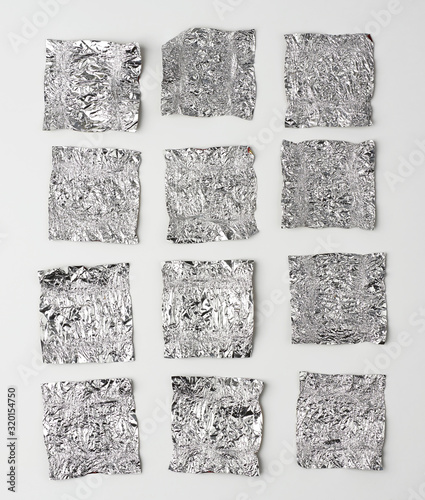 various crumpled foil used candy wrappers on a white background