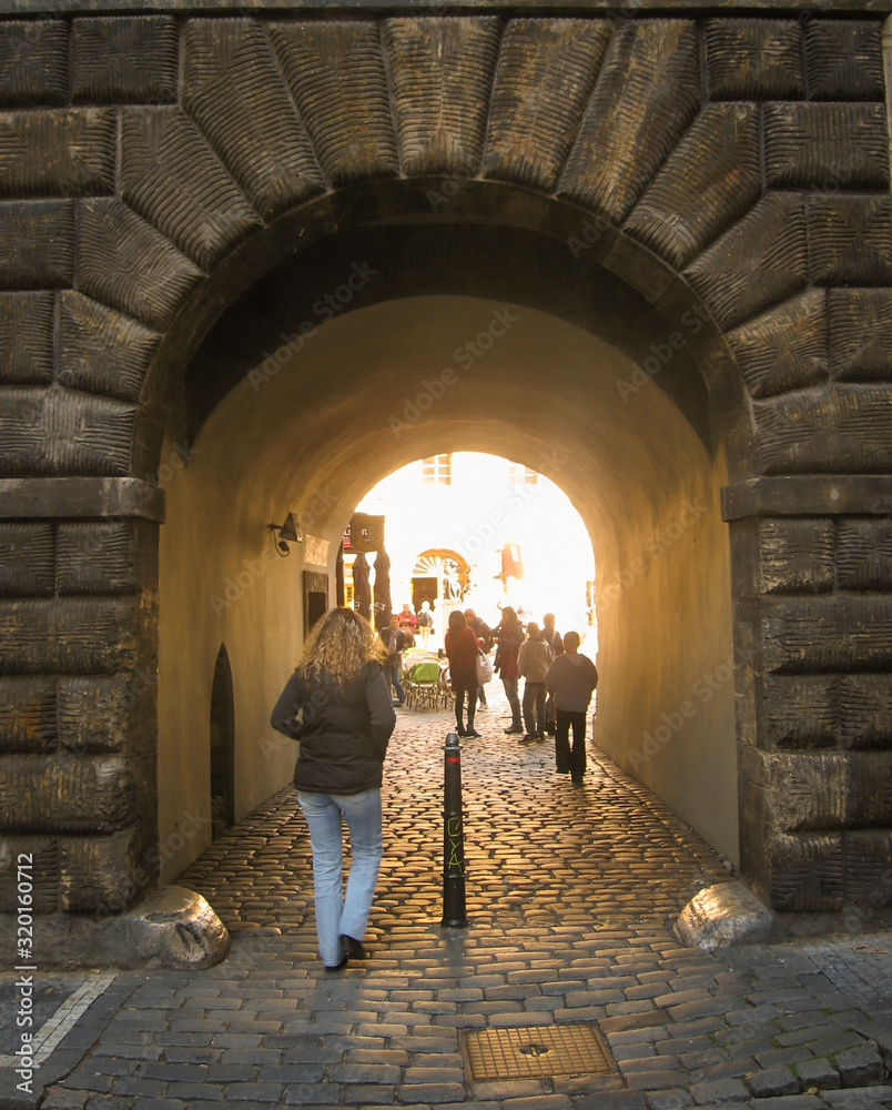 Cityscape in ancient city. Several people entering a stone arch.