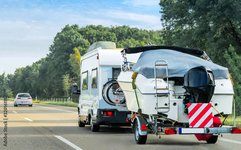 Caravan and trailer for motor boats on the road in Switzerland.