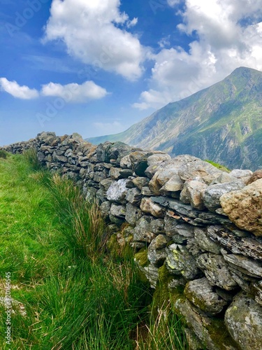 Welsh landscape mountains, stone walls, gates, lake, blue skies and green grass in Wales © Luke
