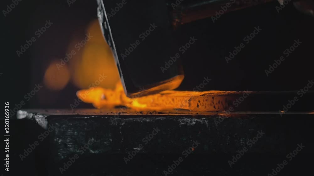 Forge workshop. Smithy manual production. Hands of smith with hammer hit on glowing hot metal, on the anvil, the forging process. Blacksmith makes iron products for manufacture of fireplace, stove.