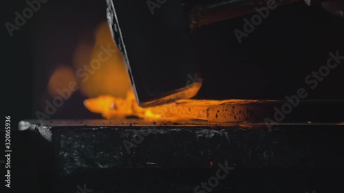 Forge workshop. Smithy manual production. Hands of smith with hammer hit on glowing hot metal, on the anvil, the forging process. Blacksmith makes iron products for manufacture of fireplace, stove.
