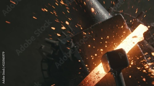 Forge workshop. Smithy manual production. Hands of smith with hammer hit on glowing hot metal, on the anvil, the forging process. Blacksmith makes iron products for manufacture of fireplace, stove.