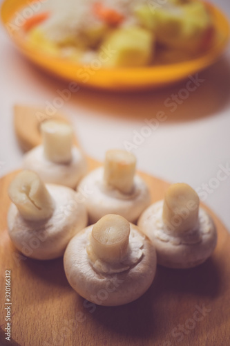 Five fresh champignons lie on a wooden board, side view.