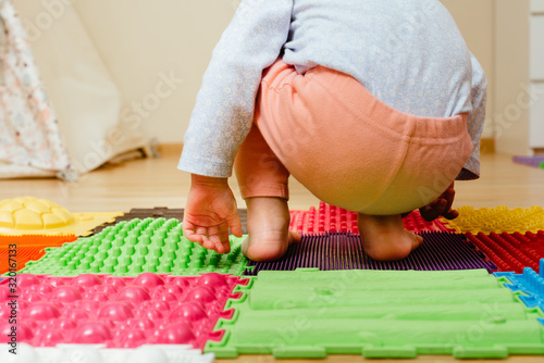 toddler plays and Massages His Feet on special massaging and orthopedic mat  close up. leg disease prevention concept