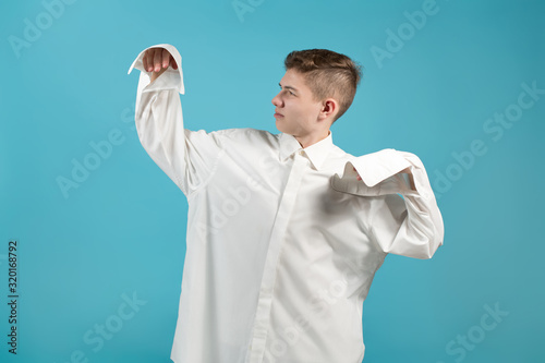 a young man in an oversized white shirt shows that his shirt is too big for him