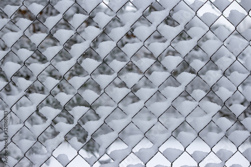 Mesh fence covered with white snow in winter