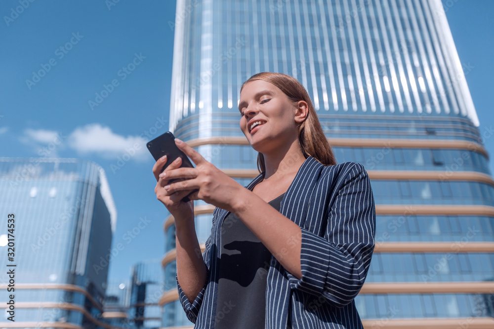 Fototapeta premium happy young woman with smartphone on modern building background