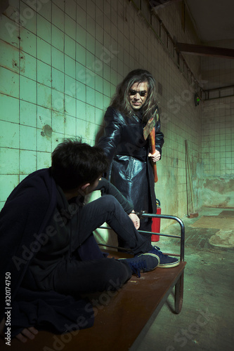 Evil kidnapper holding and controlling young man in horror place