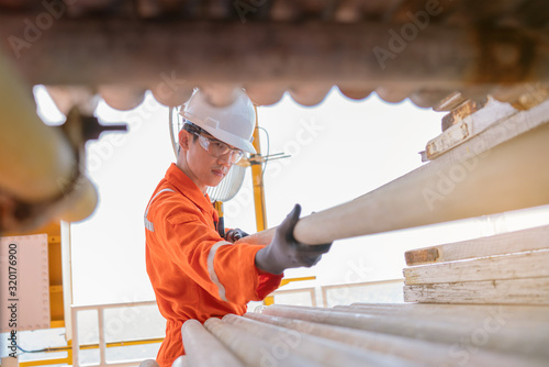 Fotografia Scaffolder pulling scaffolding on pipe rack for construction work on offshore oil and gas processing platform