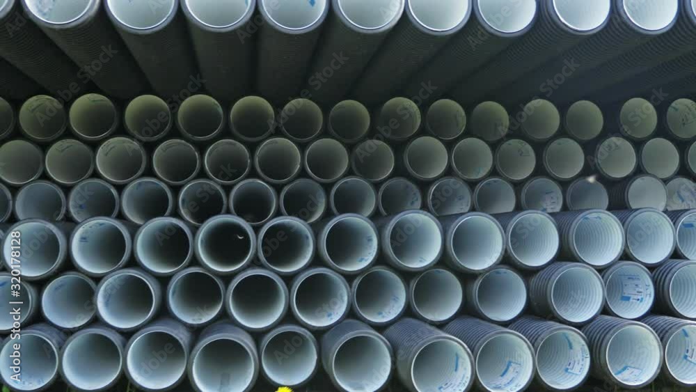 Warehouse of finished plastic pipes industrial outdoors storage site. Manufacture of plastic water pipes factory. Process of making plastic tubes on the machine tool with the use of water and air