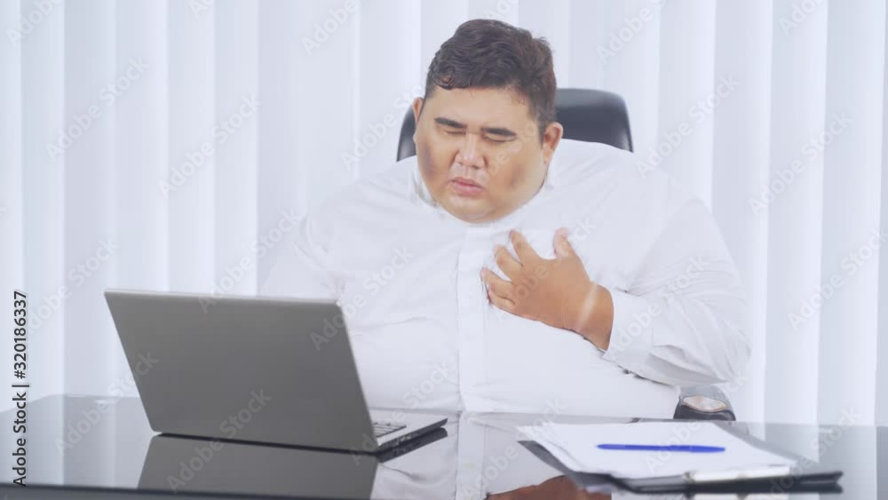 Fat young businessman getting heart attack symptom while working with laptop in the office. Shot in 4k resolution Fat young businessman getting heart attack symptom while working with laptop in the office. Shot in 4k resolution
