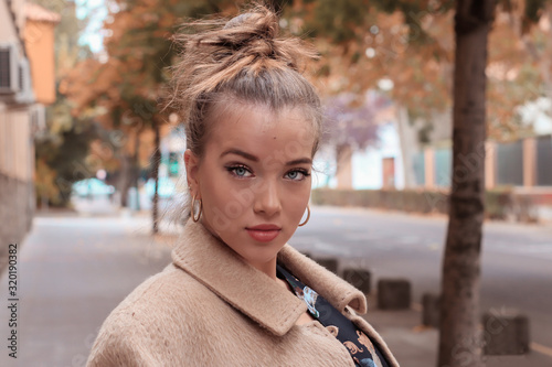 Beautiful blonde young woman with beige coat and collected hair