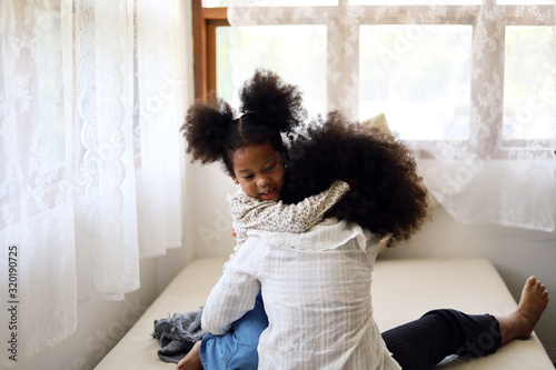 Foto The two African girl siblings are having fun and tease each other in the bedroom during the holidays