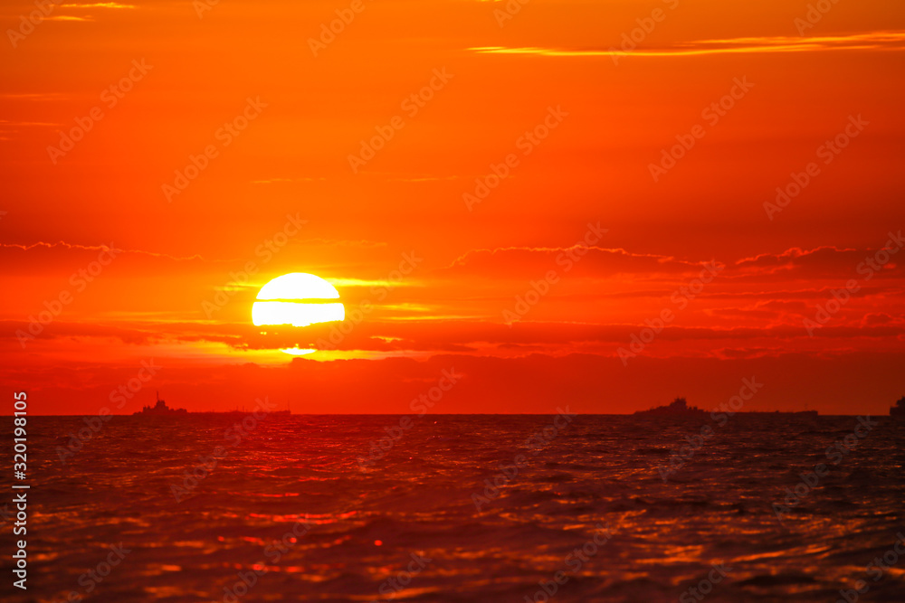 Merchant ships on the horizon against the background of a fiery red sunset Merchant ships on the horizon against the background of a fiery red sunset