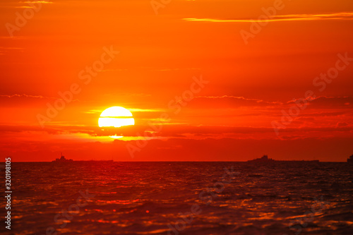 Merchant ships on the horizon against the background of a fiery red sunset