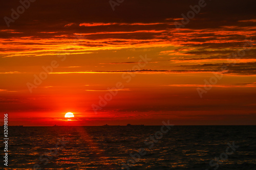 Merchant ships on the horizon against the background of a fiery red sunset