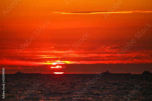 Merchant ships on the horizon against the background of a fiery red sunset