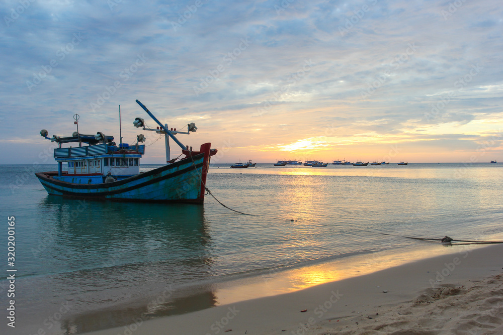 Fishing boat on a deserted beach on sunset background