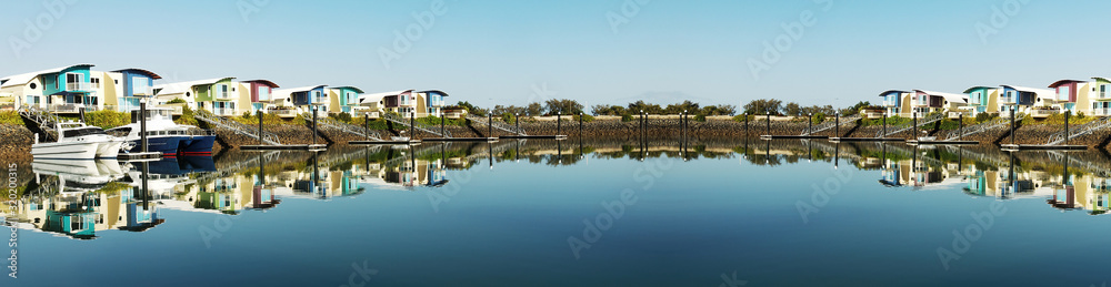 Super panoramic waterfront marina/dock/resort with boats and clear water reflections.