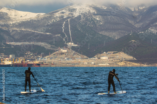 Two Men with a paddle on a blackboard in the background of winter mountains with the snow