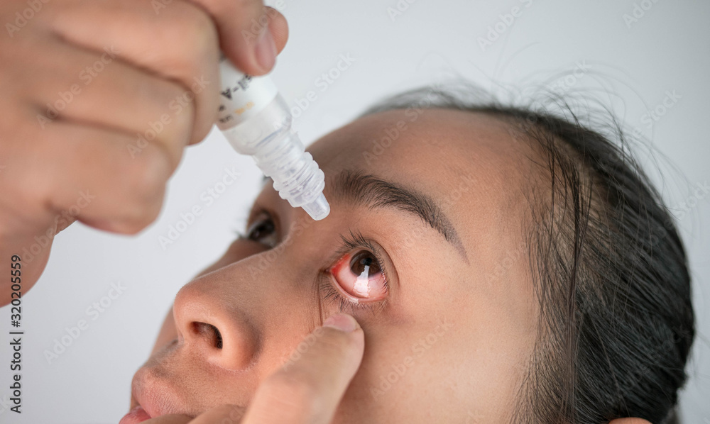 Stressed woman suffering from eye pain and dripping eye with eye drops on grey background. Stressed woman suffering from eye pain and dripping eye with eye drops on grey background.