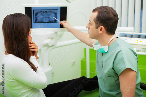 Dentist in dental office talking with female patient and preparing for treatment