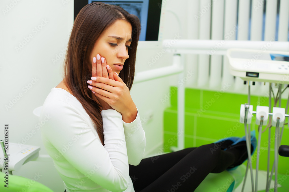 Upset woman at the dentist with constant pulsating tooth pain Upset woman at the dentist with constant pulsating tooth pain