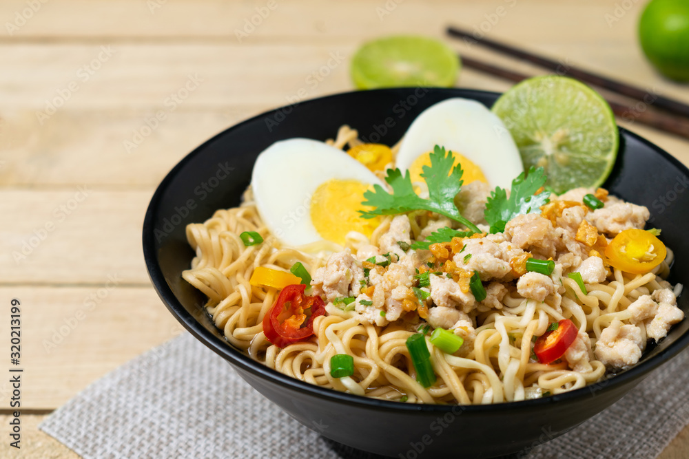 Bowl of instant noodle with minced chicken and boiled egg on wooden table. Bowl of instant noodle with minced chicken and boiled egg on wooden table.