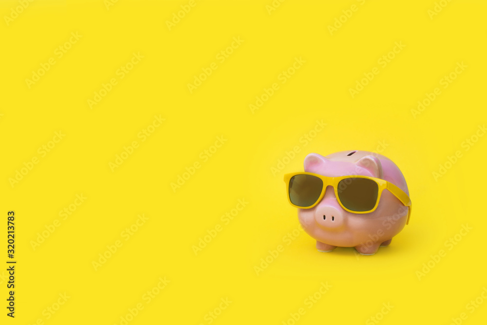 A pink piggy bank in sun glasses at a party. Yellow background.