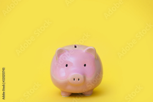 A pink piggy bank. Yellow background.