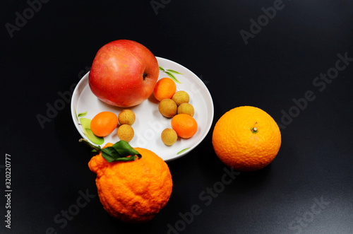 Obraz na plátně The fruit in the porcelain plate is gathered on the black background