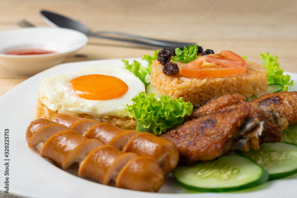 American fried rice with cucumber and lettuce in white dish on wooden table. American fried rice with cucumber and lettuce in white dish on wooden table.