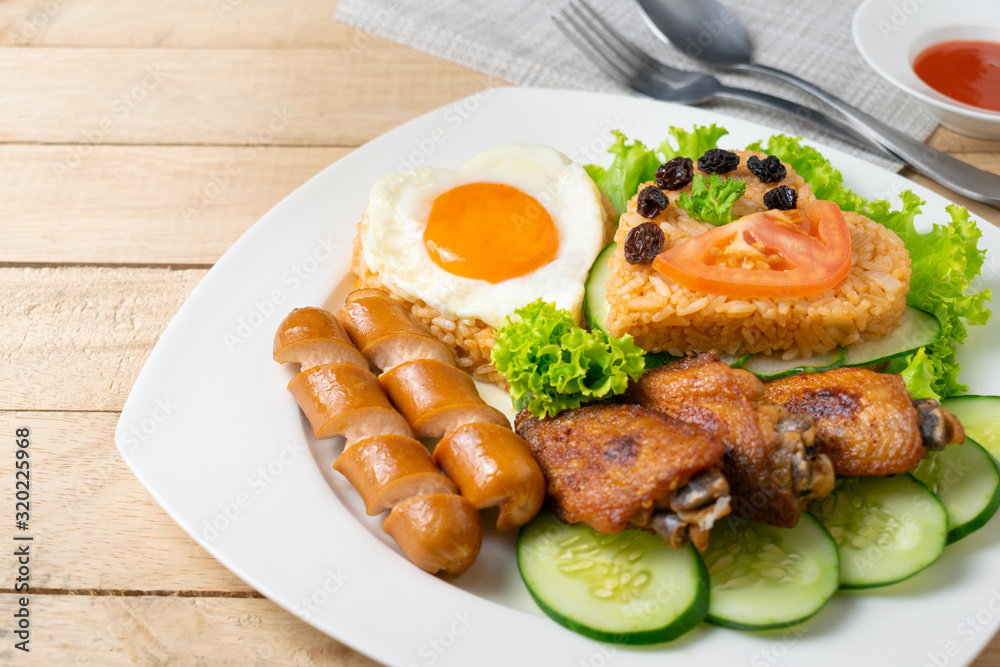 American fried rice with cucumber and lettuce in white dish on wooden table.