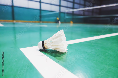 Indoor badminton competition with shuttlecock on floor and blurred background of badminton court. A game with rackets and playing indoor Batminton. selective focus, copy space. Indoor Sport concept.