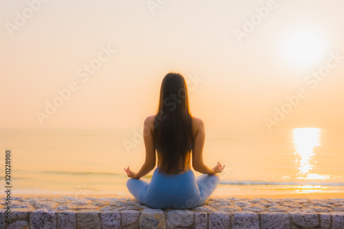 Portrait young asian woman do meditation around sea beach ocean at sunrise © siraphol