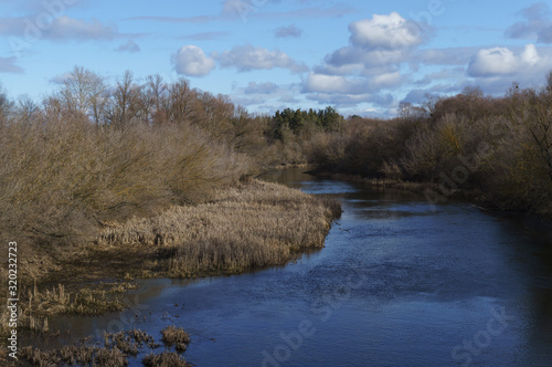 Beautiful view of the winter river on a frosty day and blue sky with clouds.