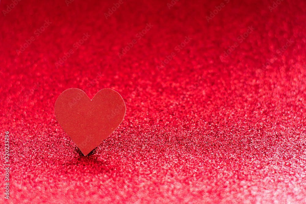 Obraz premium Red heart on a red shiny background with bokeh. Monochrome photography.