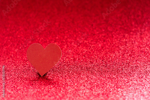 Red heart on a red shiny background with bokeh. Monochrome photography.