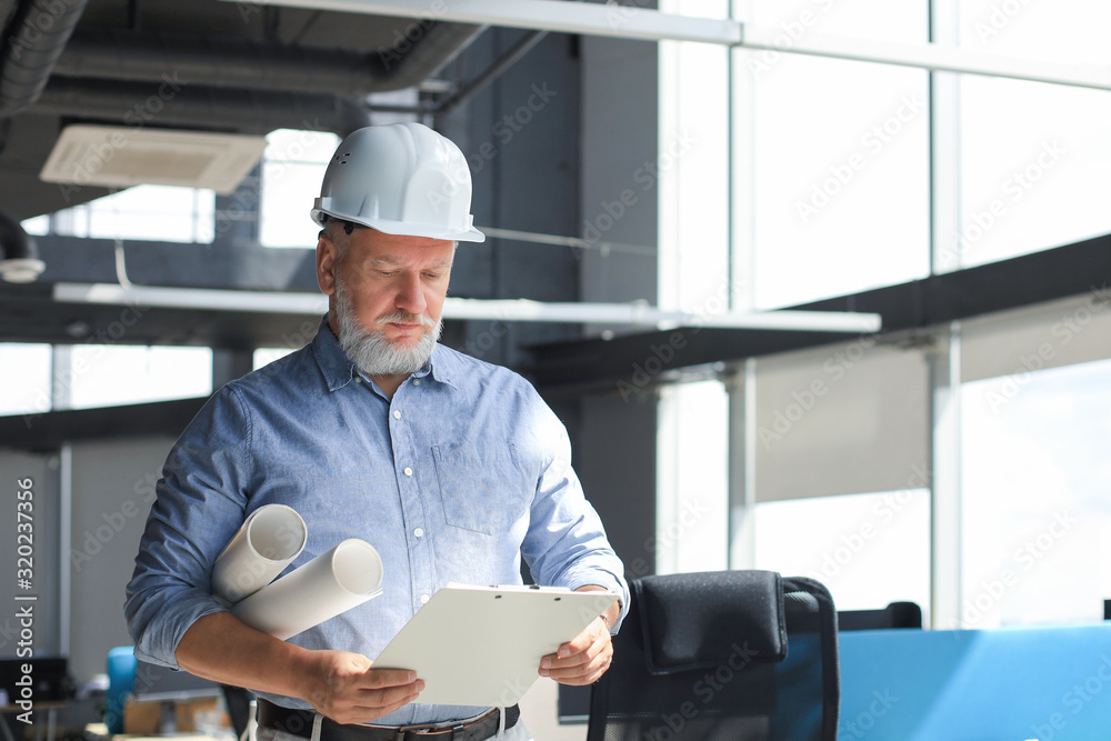 Mature architect wearing hardhat inspecting new building. Mature architect wearing hardhat inspecting new building.