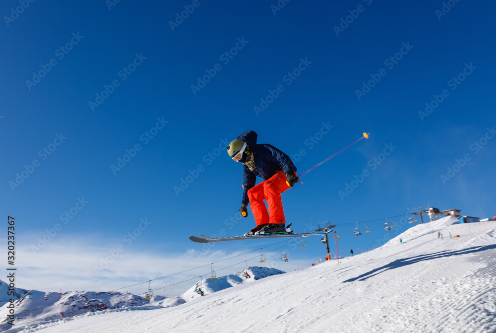 Skier jumps in snow park against the blue sky in Livigno ski resort, Italy
