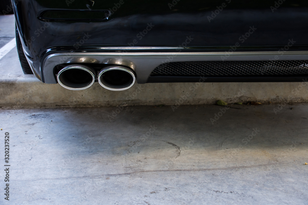 Double exhaust pipe for black car in parking lot. Double exhaust pipe for black car in parking lot.