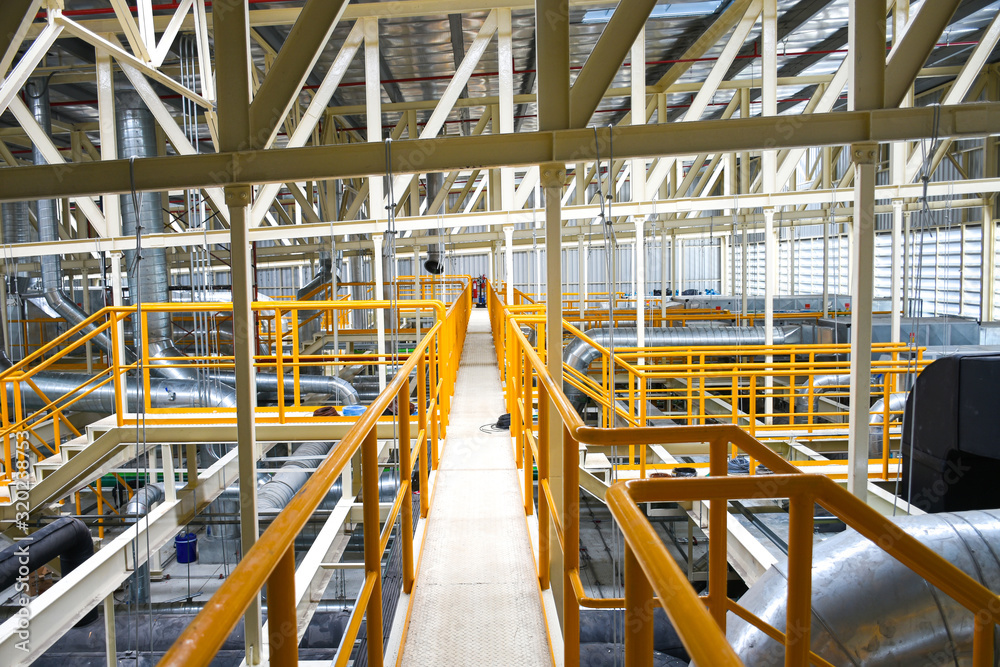 Industrial walk way with yellow handrail and steel structure roof inside factory. Industrial walk way with yellow handrail and steel structure roof inside factory.